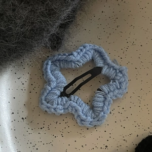 Gros plan sur une pince à cheveux étoile en tricot bleu clair montrant la texture du tissu