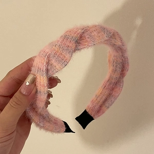 Détail d'un serre-tête tricoté rose montrant la texture douce de la laine tressée