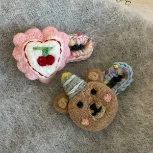 Detail view of handmade wool felt hair clips with cute pink heart and brown bear designs