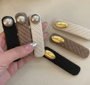 Macro detail of handmade knitted BB hair clips with golden metal tags and knit texture