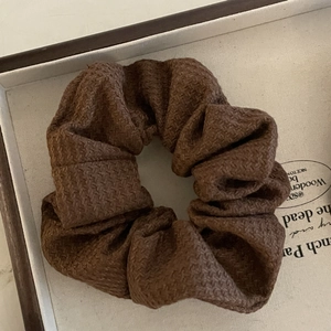 Detailed view of brown textured fabric scrunchie with soft ribbed knit material in a gift box