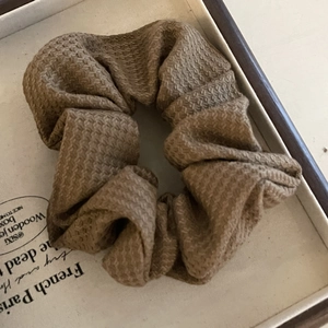 Brown textured fabric scrunchie with honeycomb weave in a vintage wooden tray