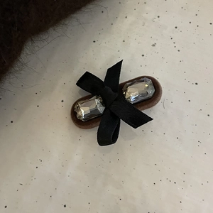 Detailed macro view of velvet bow hair clip featuring rectangular zircon crystals on a brown base