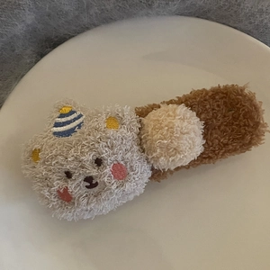 Gros plan d'une barrette à cheveux en peluche avec un petit ours et un chapeau de fête
