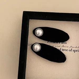 Pair of black velvet oval hair clips with large white pearl accents on vintage card