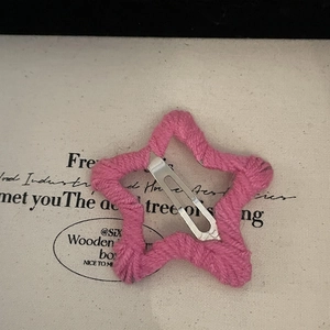 Détail de la pince à cheveux étoile tricotée rose avec clip métallique argenté