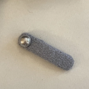 Vue détaillée d'une barrette à cheveux en peluche gris foncé avec une perle argentée