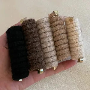 Detail of wool-woven spiral hair ties in five earthy tones with golden metal ends