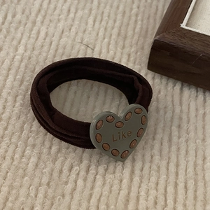 Elastic coffee hair tie with heart-shaped 'Like' charm on a cozy knitted background