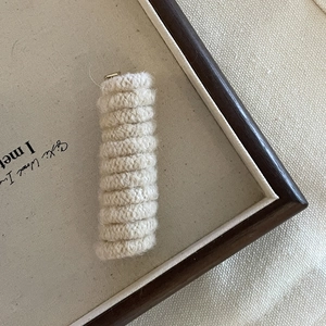 Knitted spiral hair tie in cream white on a minimalist vintage display board