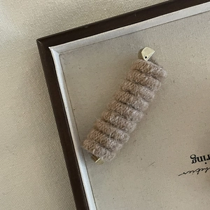 Brown wool-wrapped telephone wire hair tie with elegant gold metal tips in a gift box
