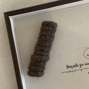 Close-up of dark brown knitted duckbill hair clip with wave texture and cozy wool finish