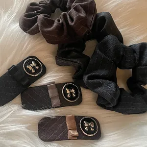 Detail of checkered fabric hair scrunchies and bow clips on a white plush background