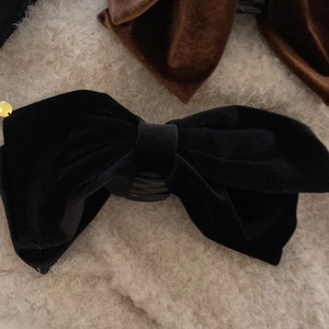 Elegant small black velvet bow hair claw clip for women on a white plush background