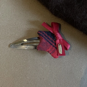 Detail of red and blue plaid star hair clip with red ribbon bow and golden metal tag