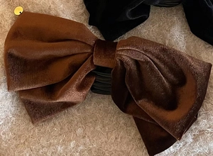 Detailed macro view of a brown velvet bow hair claw clip with golden metal accent