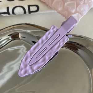 Textured lavender metal hair clip with wavy pattern on silver tray, minimalist accessory
