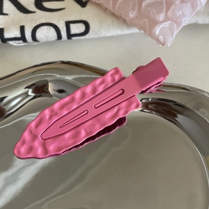Detail of pink matte metal hair clip with unique wavy texture on a silver tray
