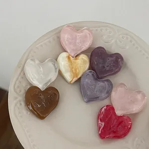 Colorful heart-shaped acetate hair clips with marble texture on a decorative ceramic plate
