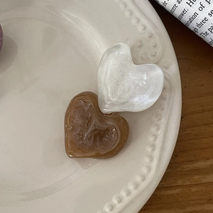Elegant marble heart hair clips in cream white and amber brown on a ceramic tray