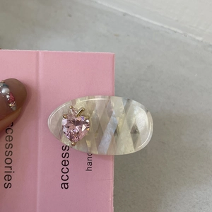 Détail d'une pince à cheveux avec cœur rose en cristal et base en acétate goutte d'eau