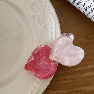 Detailed macro view of heart-shaped marble resin hair clips on a vintage ceramic plate
