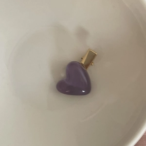 Detail of a purple heart-shaped hair clip with a gold metal duckbill base on a white dish