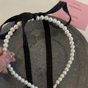 Elegant pearl headband with a black ribbon bow for women in a vintage Hepburn style