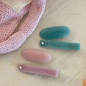 Detail of four acetate hair clips with marble texture, rhinestones and gummy colors
