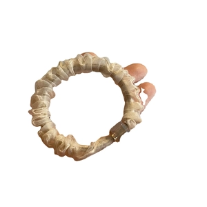 Elegant champagne gold organza scrunchie with pleated texture and decorative brown buckle