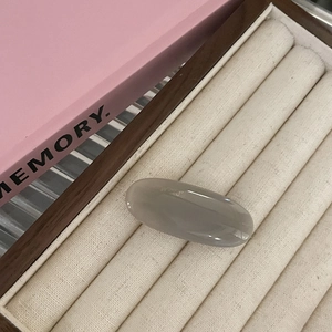 Minimalist grey oval gummy hair clip in a smooth translucent resin on a jewelry display