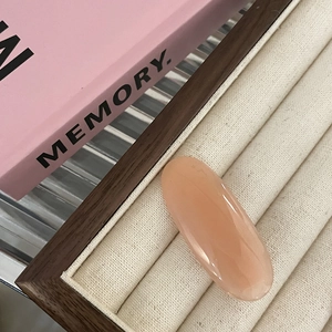 Macro shot of an oval pink resin gummy hair clip placed on a beige fabric jewelry tray