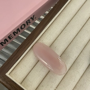 Macro shot of oval translucent pink gummy hair clip on a beige velvet jewelry tray