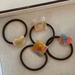 Lot de quatre chouchous en acétate pastel avec breloques marbrées sur plateau beige