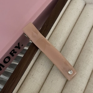 Close-up of a dusty pink resin rectangular hair clip with a single pearl rhinestone detail