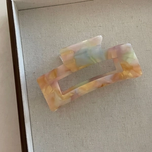 Détail d'une pince à cheveux carrée évidée en acétate avec une texture marbrée colorée