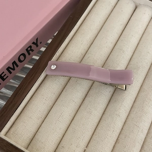 Close-up of a dusty pink resin hair clip with a single white rhinestone in a velvet box