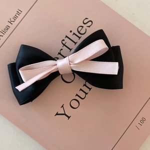 French style double layer bow hair clip in black and pink ribbon on a book