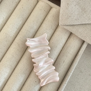 Close-up of pearl white pleated hair clip with elegant iridescent resin texture