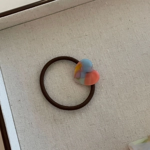 Gros plan d'un charme en résine mosaïque en forme de cœur sur un élastique marron