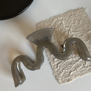 Détail de la grande pince à cheveux ondulée grise translucide avec un ressort métallique