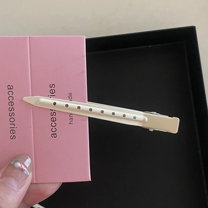 Détail d'une pince à cheveux beige avec perforations sur une carte rose