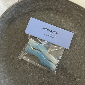 Close-up of wavy blue and white marble resin hair clips on purple display card
