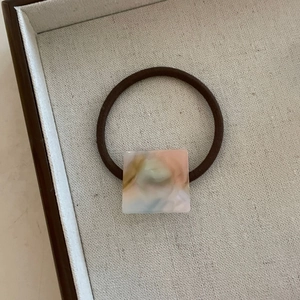 Vue macro d'un élastique marron avec perle carrée en résine à texture marbrée