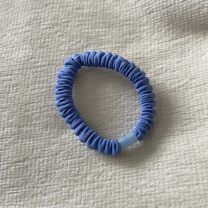 Close-up of sky blue scrunchie with pleated fabric texture and elastic design