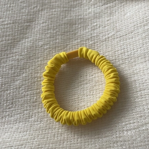 Macro detail of elastic yellow scrunchie texture with matching plastic fastener