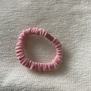 Detail of pink pleated fabric hair scrunchie with matte clip on waffle texture background