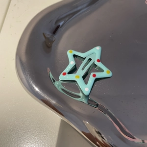 Cute light blue star hair clip with colorful polka dots on a reflective silver tray