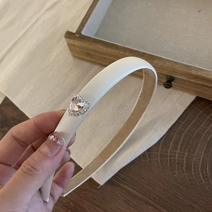Close-up of cream leather padded headband featuring a pink rhinestone heart detail