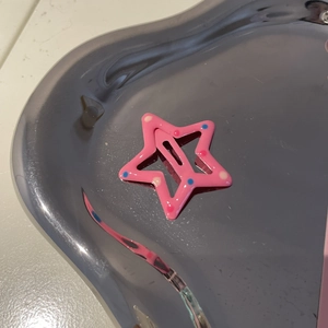 Pink star-shaped hair clip with colorful polka dots on a silver heart-shaped tray